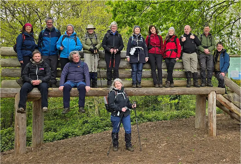 Groepsfoto in een bos op een grote houten bank
