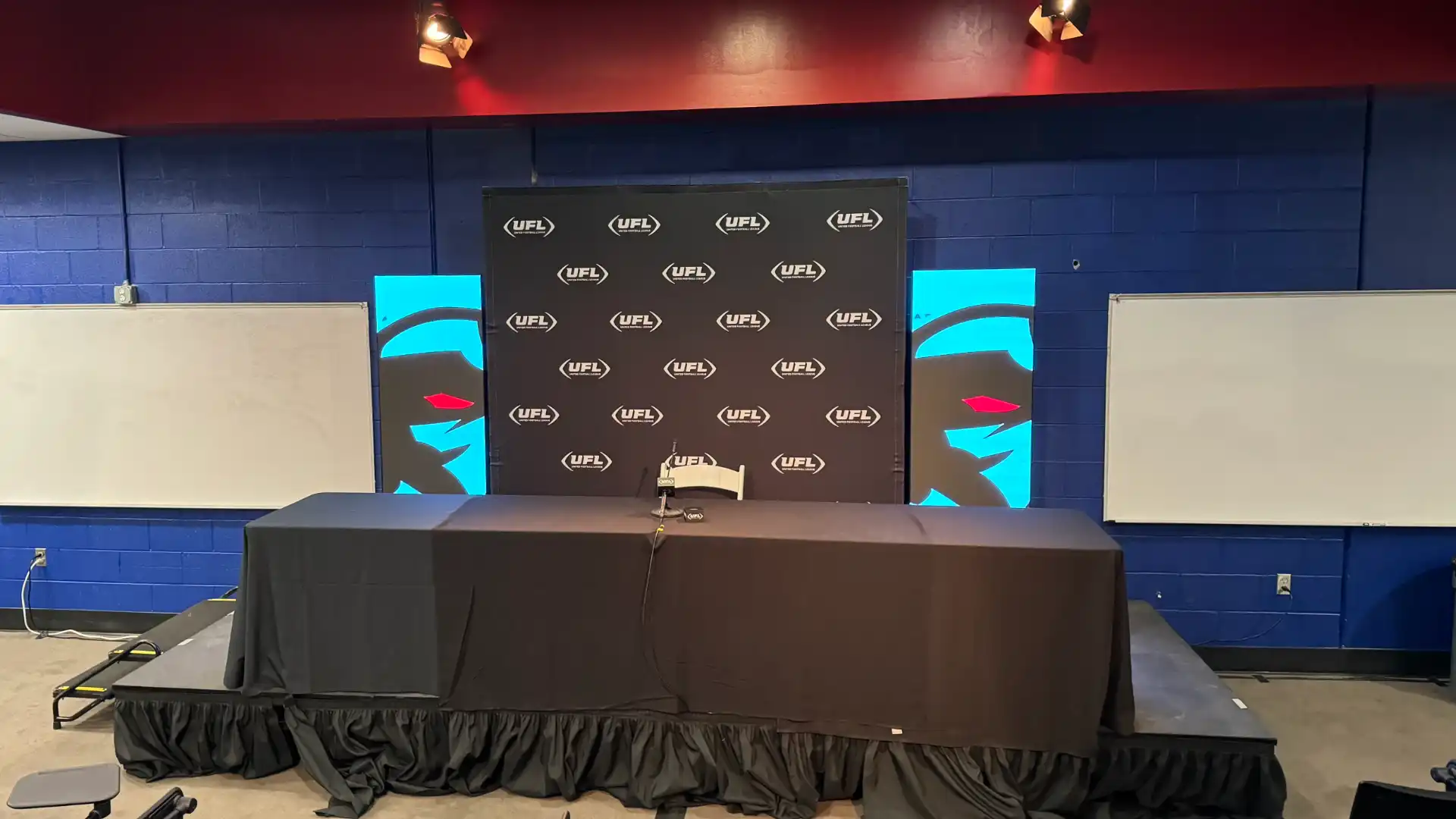 Pressor room with black and white step and repeat banner with two CMG visuals led video wall posters.