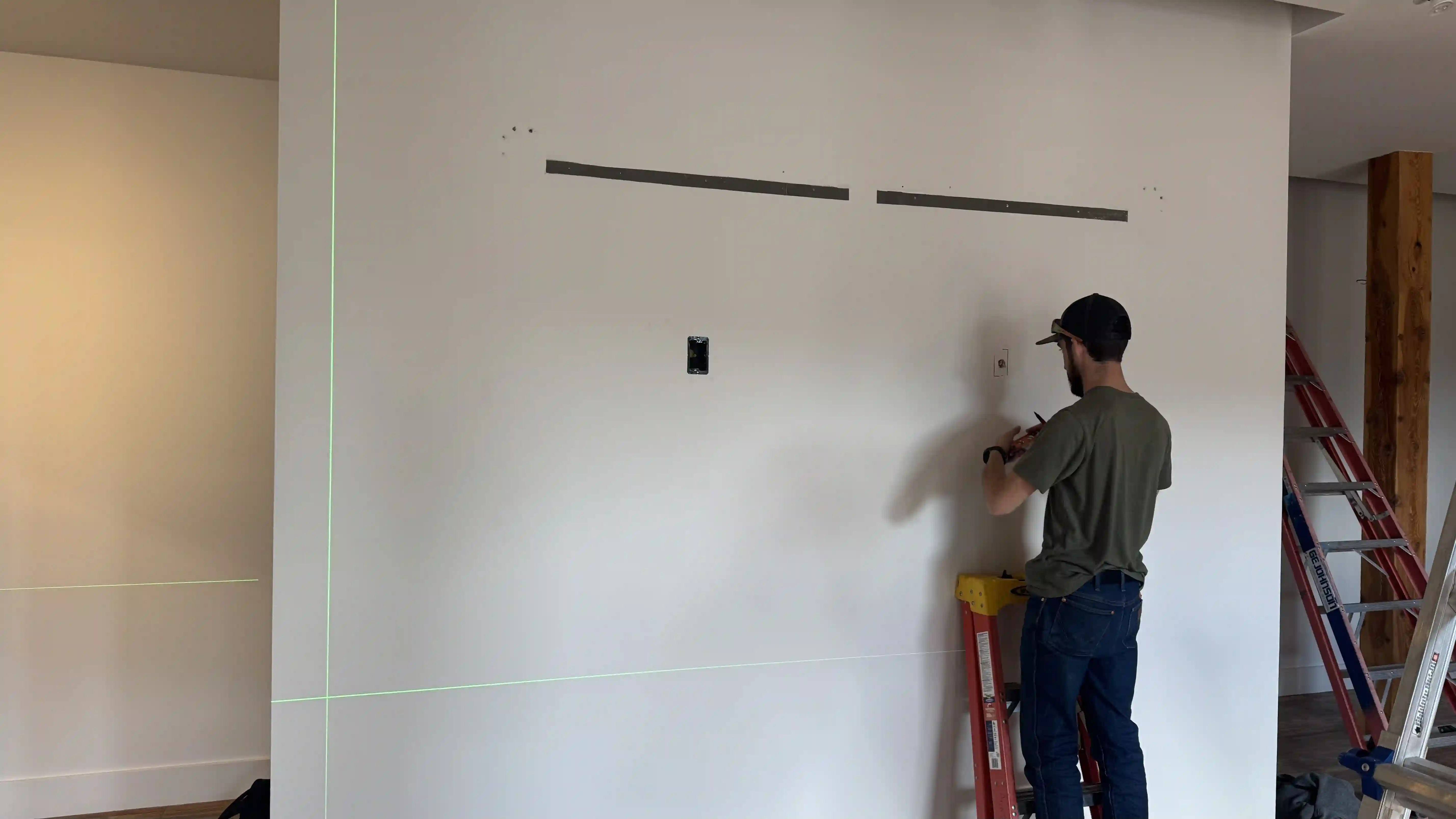 Technician preparing electrical wiring and mounting structure for LED video wall installation at Jackson Hole Jewelry Company retail store.