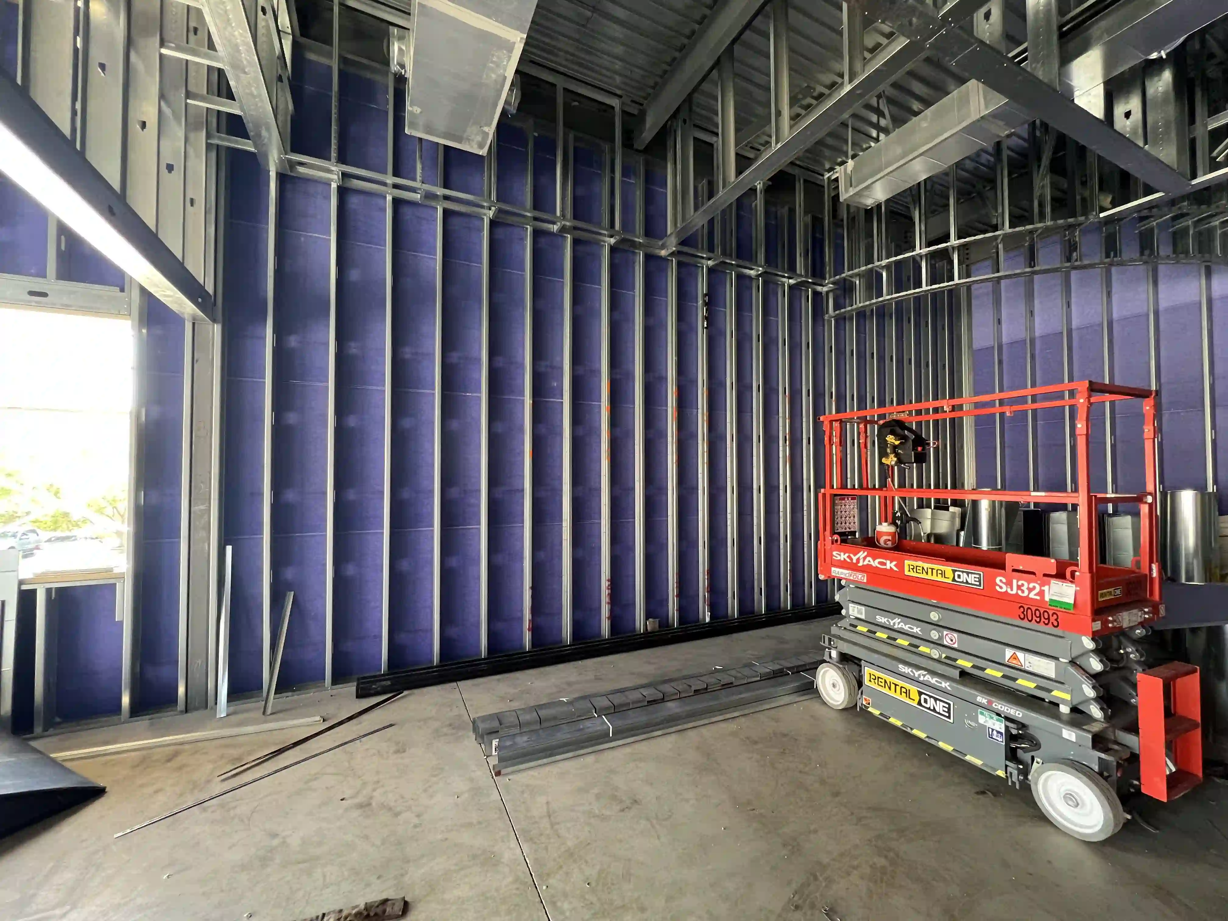 Pre-construction site prepared for CMG Visuals LED video wall installation, showing steel framing, lift equipment, and unfinished interior space.