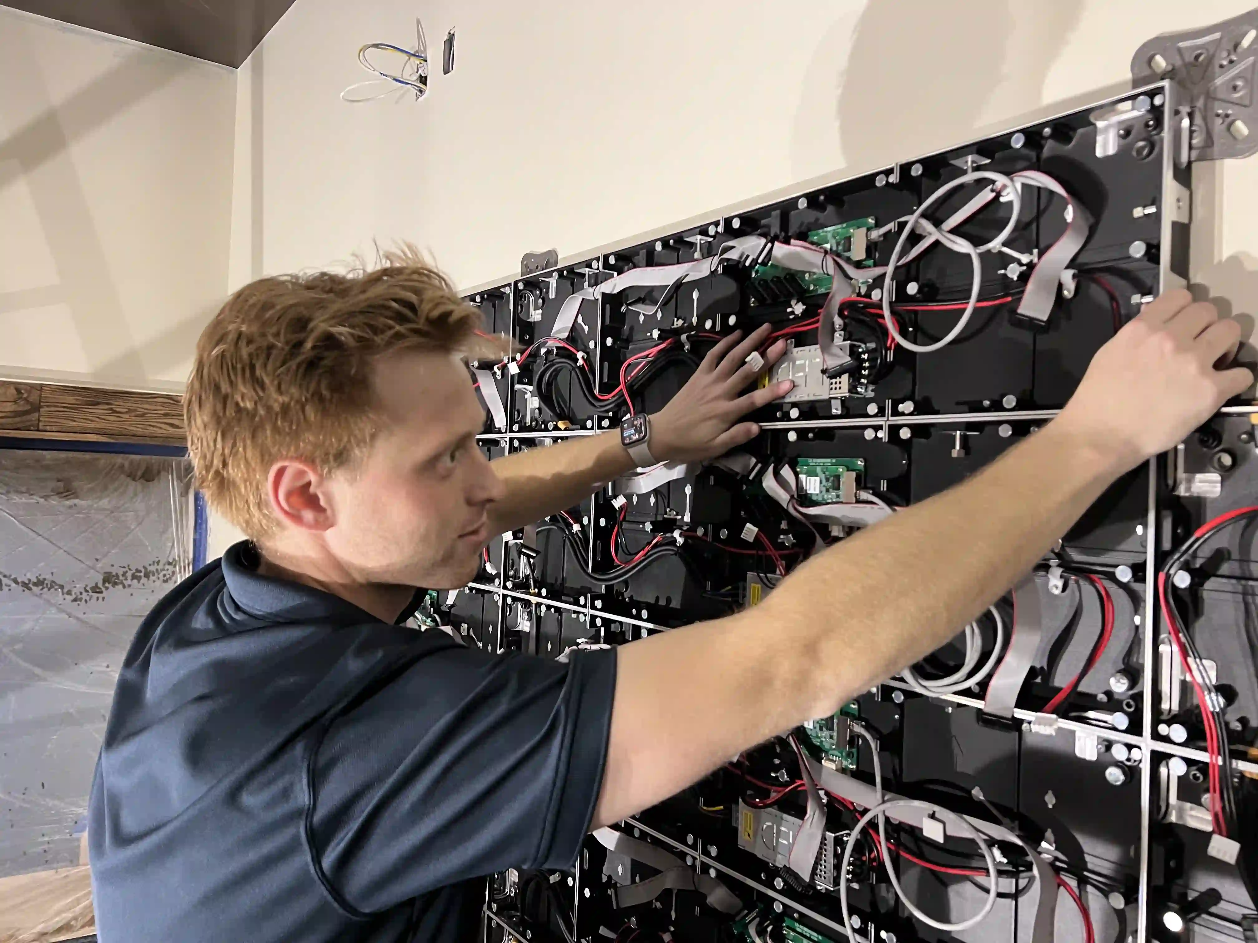Technician from CMG Visuals aligning LED display panels during installation, ensuring precise fit and high-quality video performance.