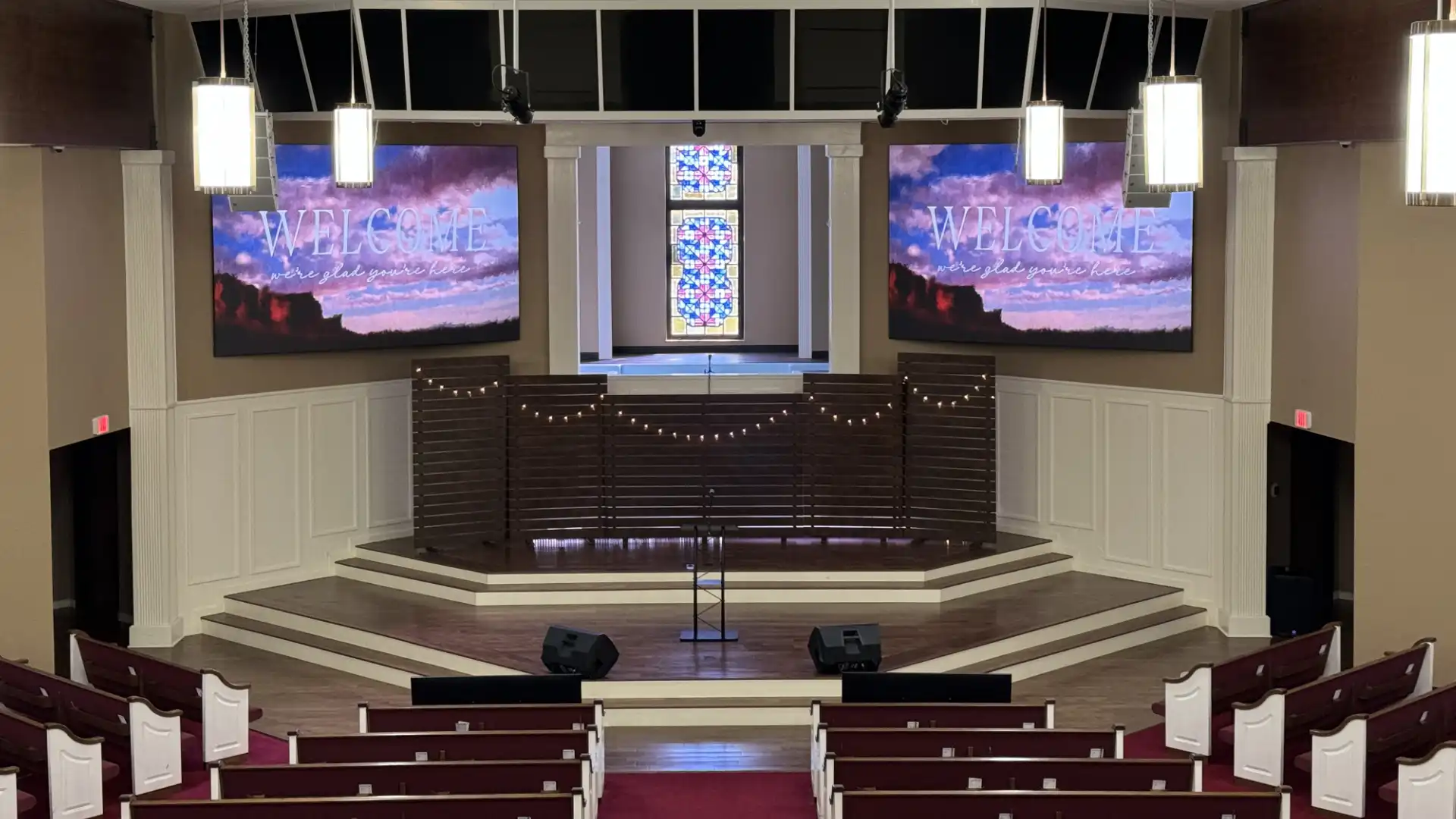 Church sanctuary with dual LED video walls flanking the stage, “Welcome” graphics displayed—worship center LED screen installation and AV upgrade.