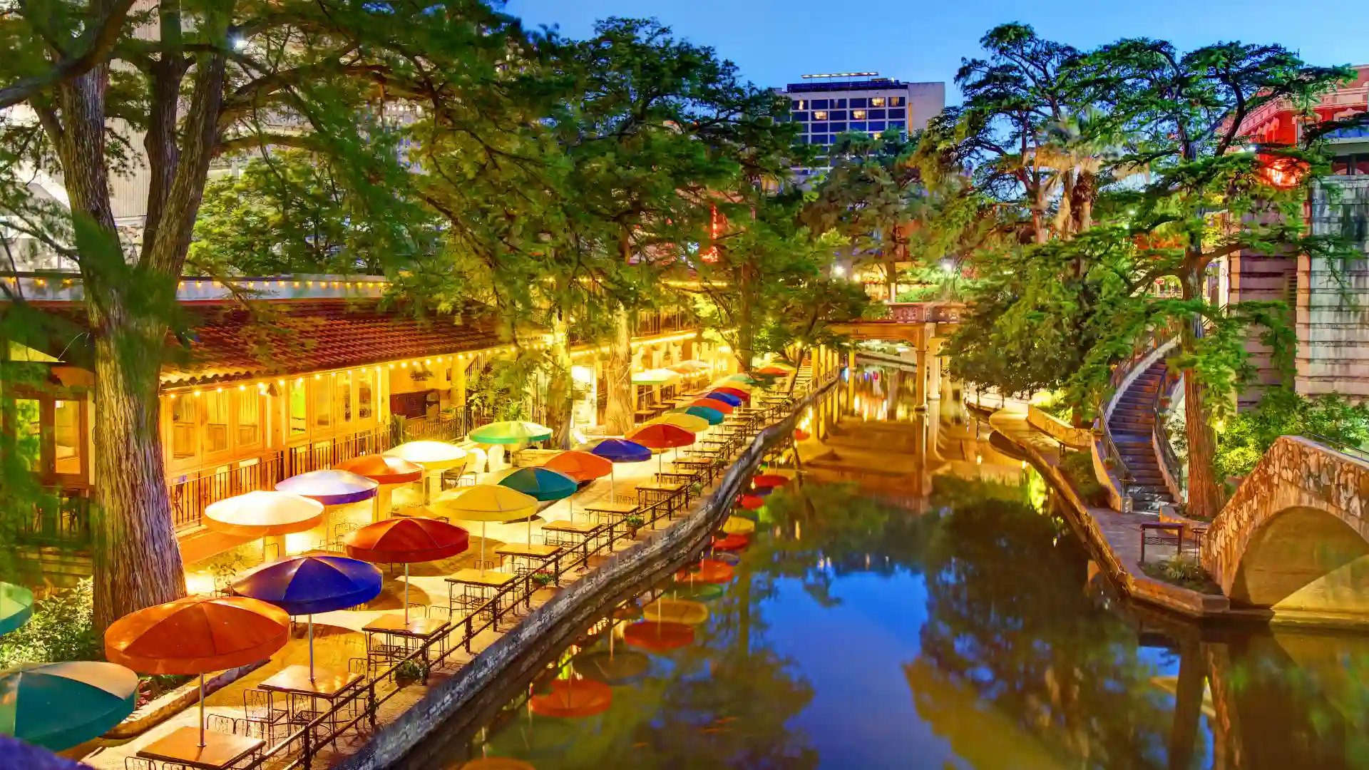 San Antonio River Walk with restaurants and colorful umbrellas at night