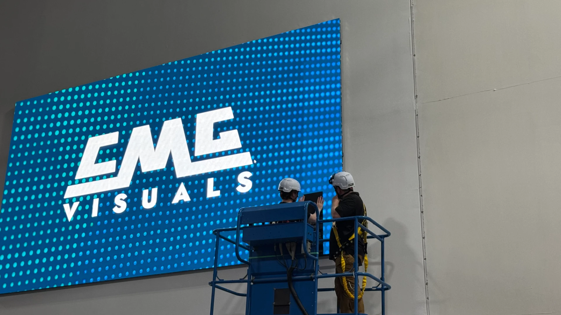 Crew on lift installing LED video wall showing CMG Visuals logo