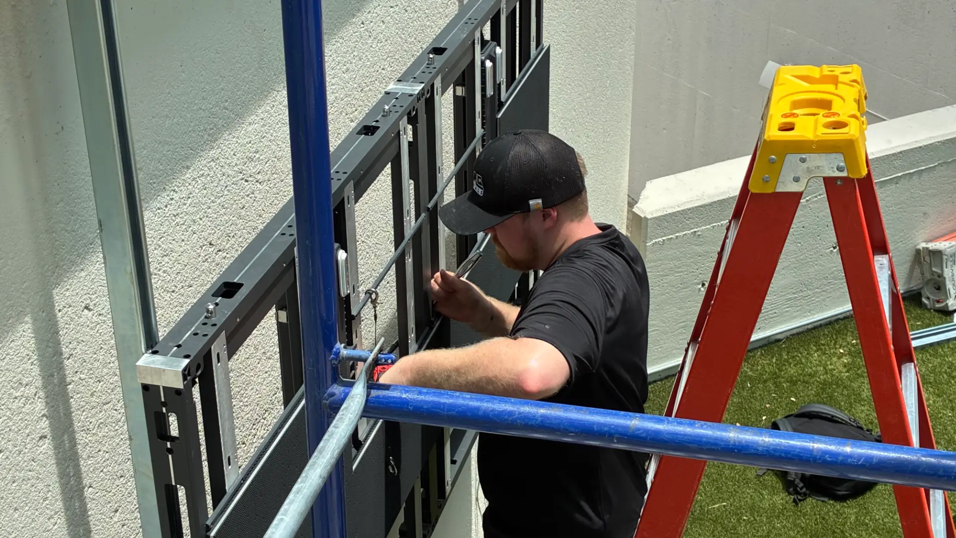 CMG Visuals technician installing outdoor LED panels on scaffolding