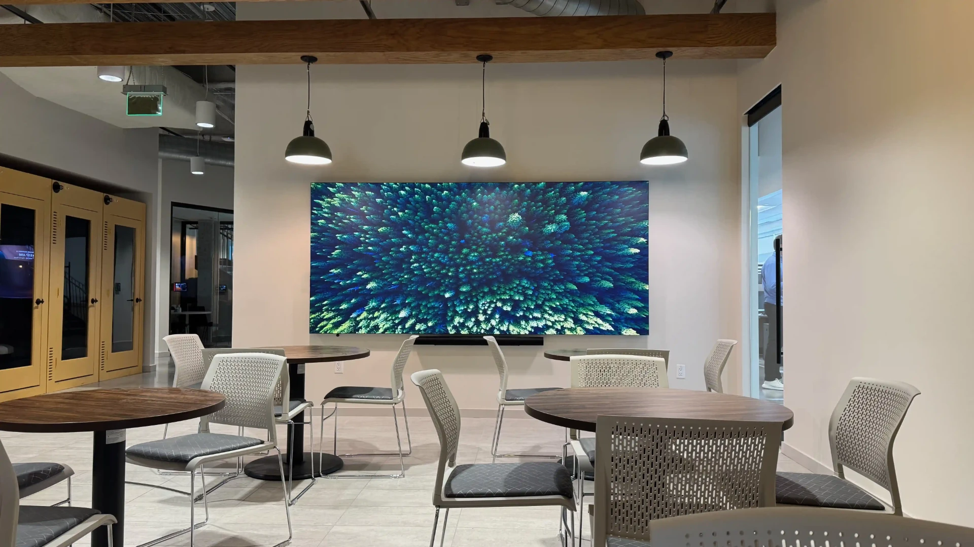 P0.9 MicroLED video wall installed by CMG Visuals in a modern corporate break room displaying high-resolution content. 
