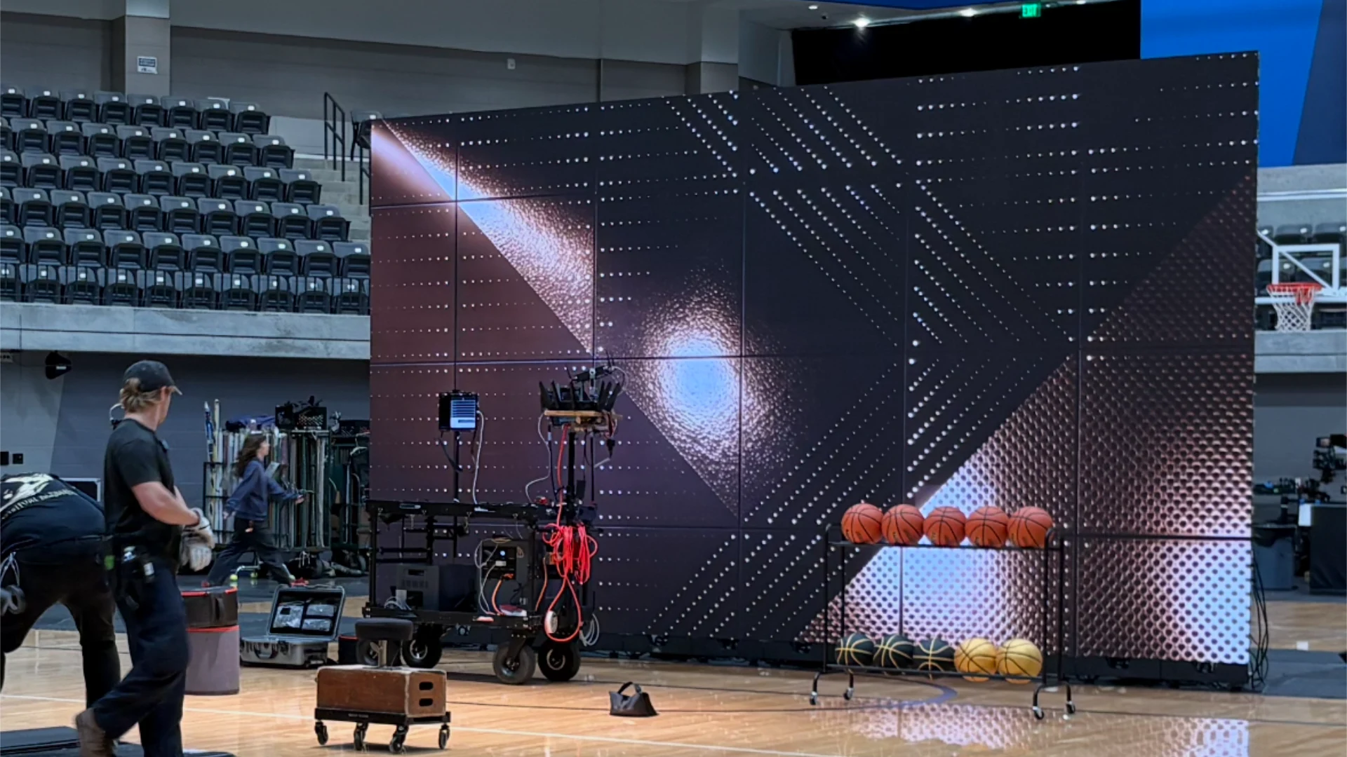 Crew assembling a CMG Visuals LED video wall for the BetMGM shoot, screen lit with a starburst graphic.