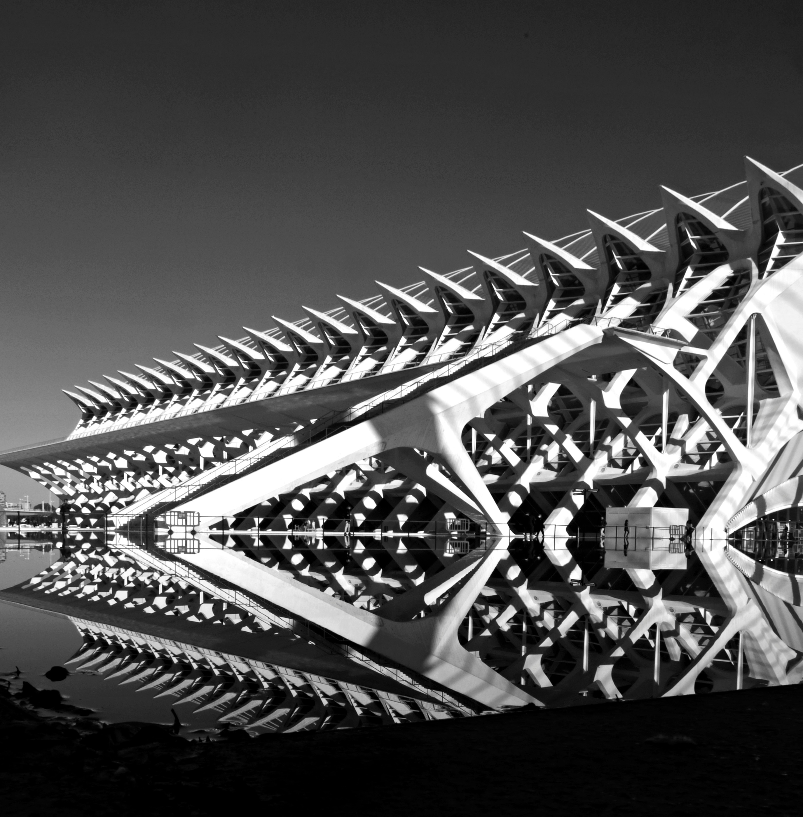 Modern architectural structure with angular supports reflected symmetrically in calm water.