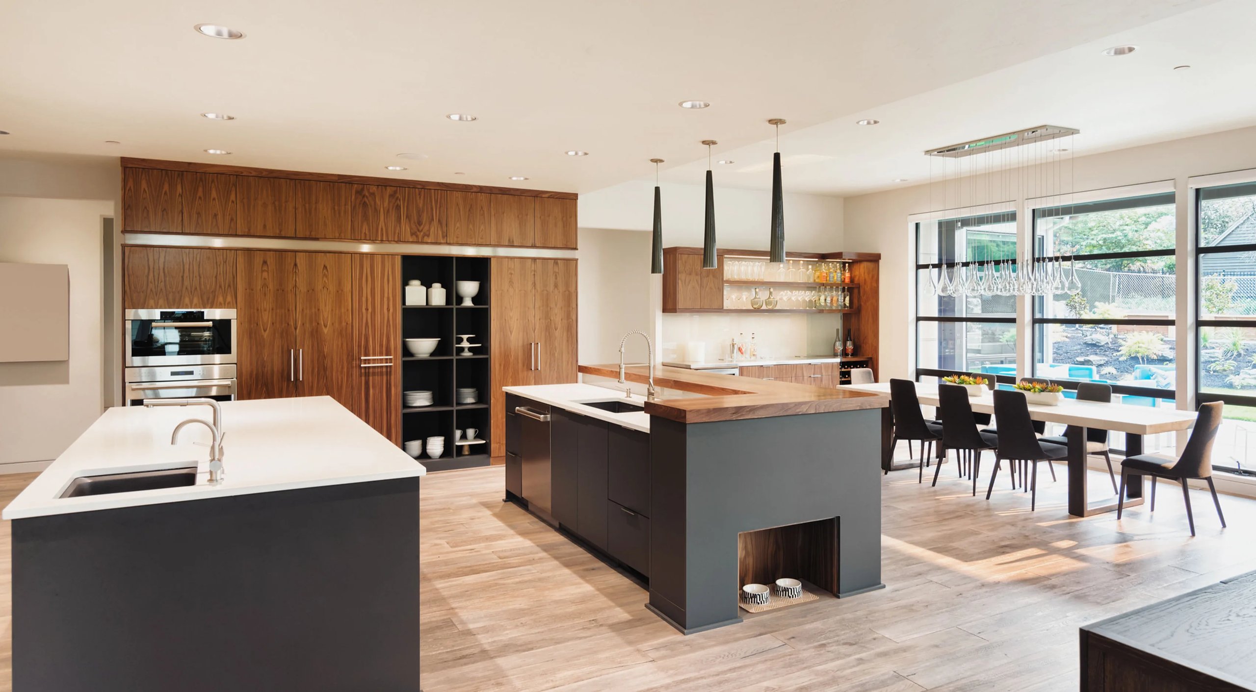Modern kitchen and dining area with wood and black cabinetry, large island, and floor-to-ceiling windows