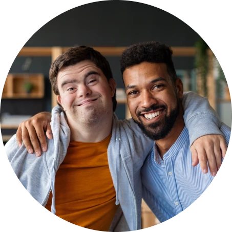 Two men smiling with their arms around each other in a friendly embrace indoors.