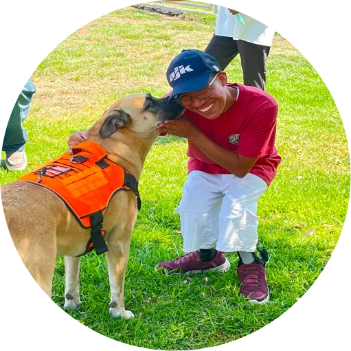 Two smiling adults with Down syndrome standing outdoors, one wearing glasses and a striped blazer, the other in a black Teddy Bears graphic t-shirt.