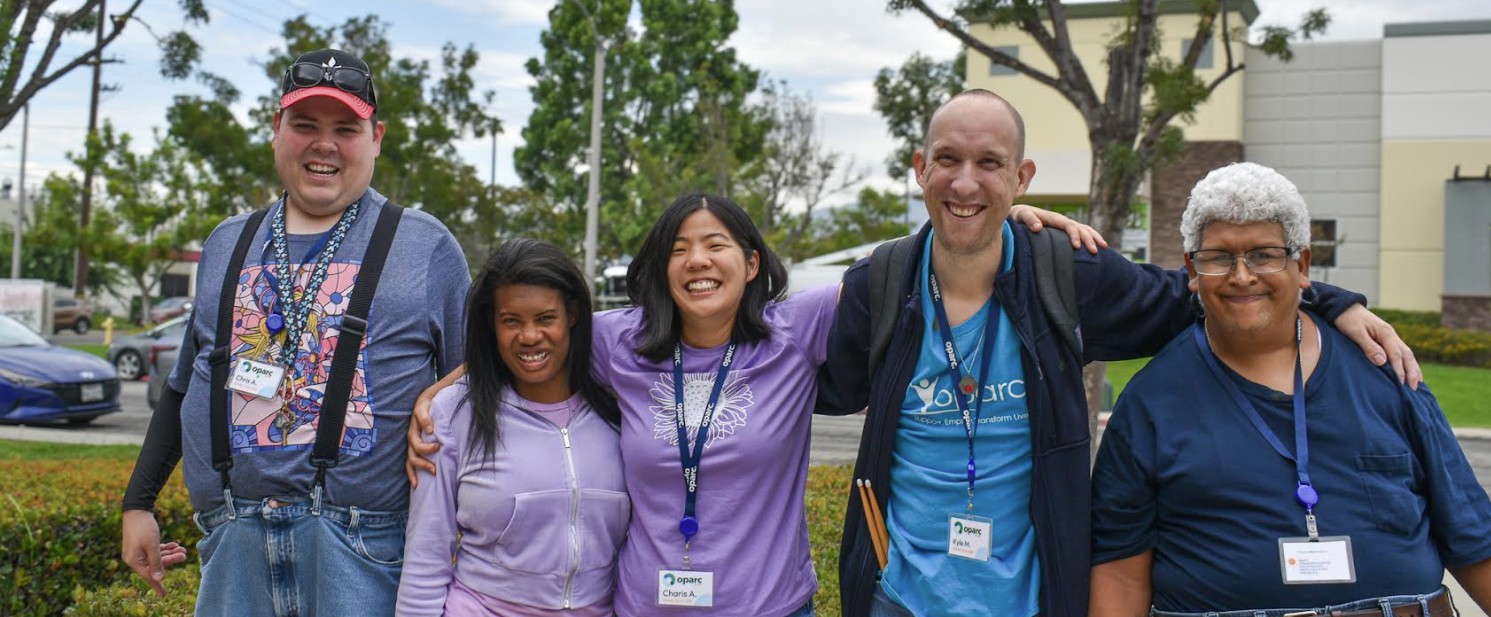 Five people standing outdoors smiling at the camera.