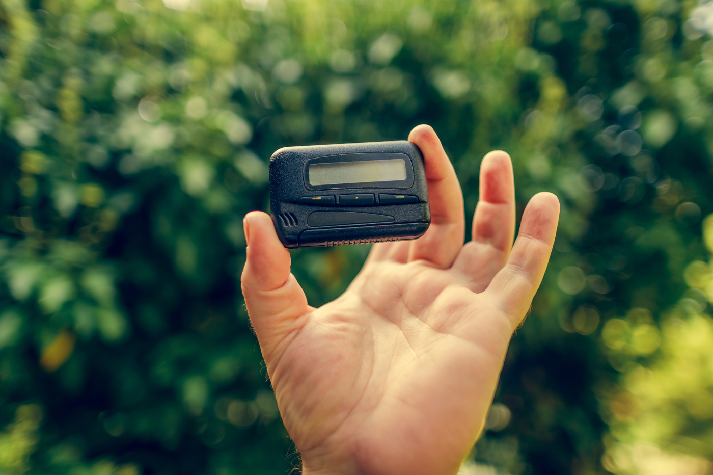 Hand holding up a black old-fashioned pager