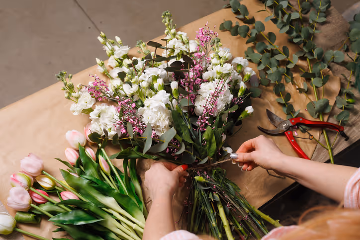 Zoom sur des mains qui composent un bouquet de fleurs