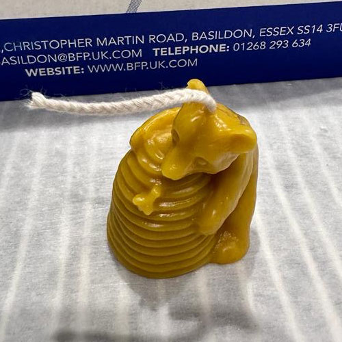 This charming beeswax candle features a classic bee skep and a curious bear caught in the act of savoring honey — a celebration of nature’s sweetest friendship.