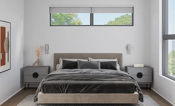 Modern bedroom with a beige upholstered bed, dark gray bedding, matching nightstands with decor, and a horizontal window above the bed.