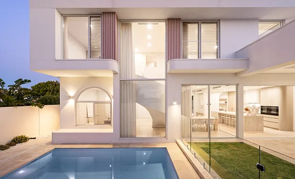 Modern two-story house with large windows, indoor staircase, glass sliding doors, and a swimming pool in the foreground.