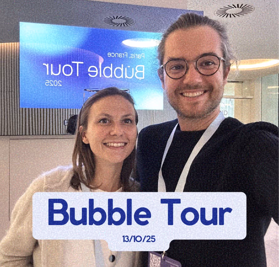 Deux personnes souriantes portant des badges d'identification lors d'un événement appelé Bubble Tour, avec un écran affichant Bubble Tour Paris 2025 en arrière-plan.