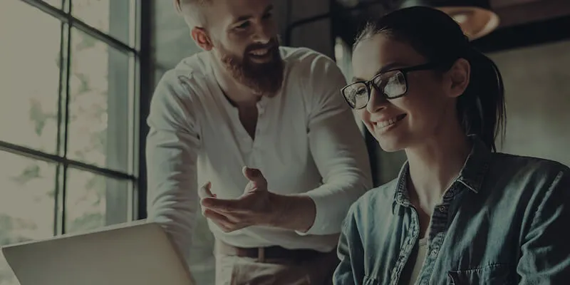 a man discussing something over the shoulder of a woman working on the laptop
