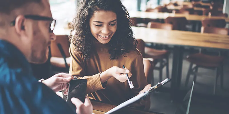 a woman pointing out using a pen onto the paper to a man