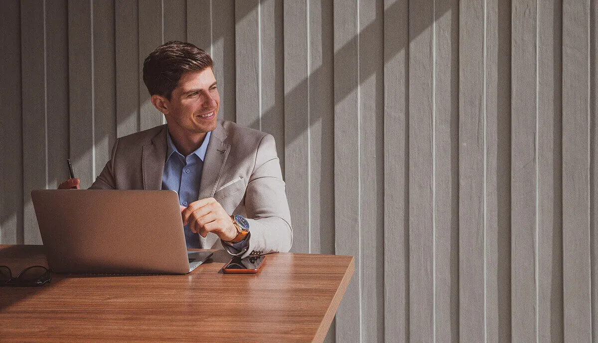 a man gazing outside while sitting in front of his laptop
