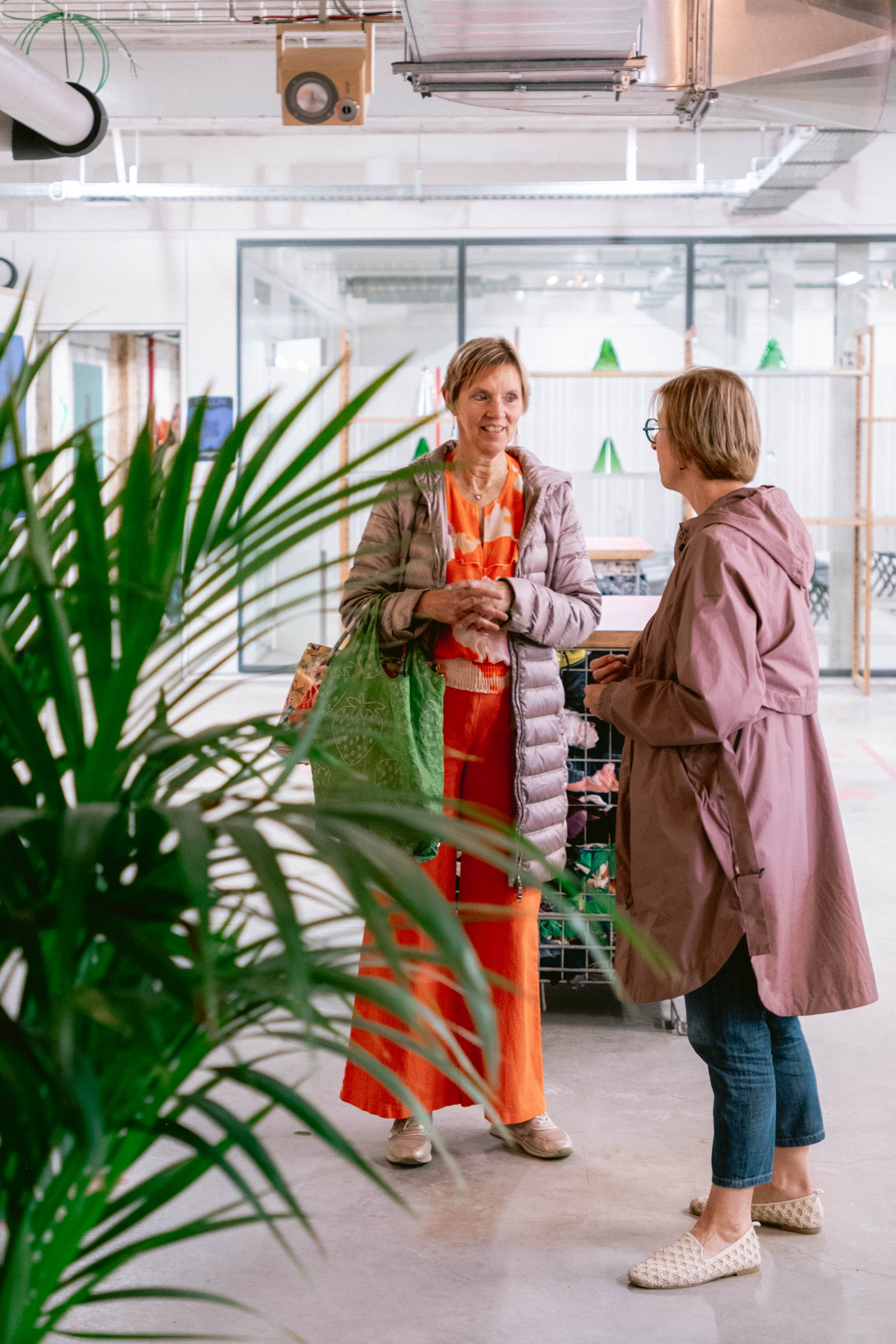 A group of people socializing and laughing around a table in a bright, modern indoor space.