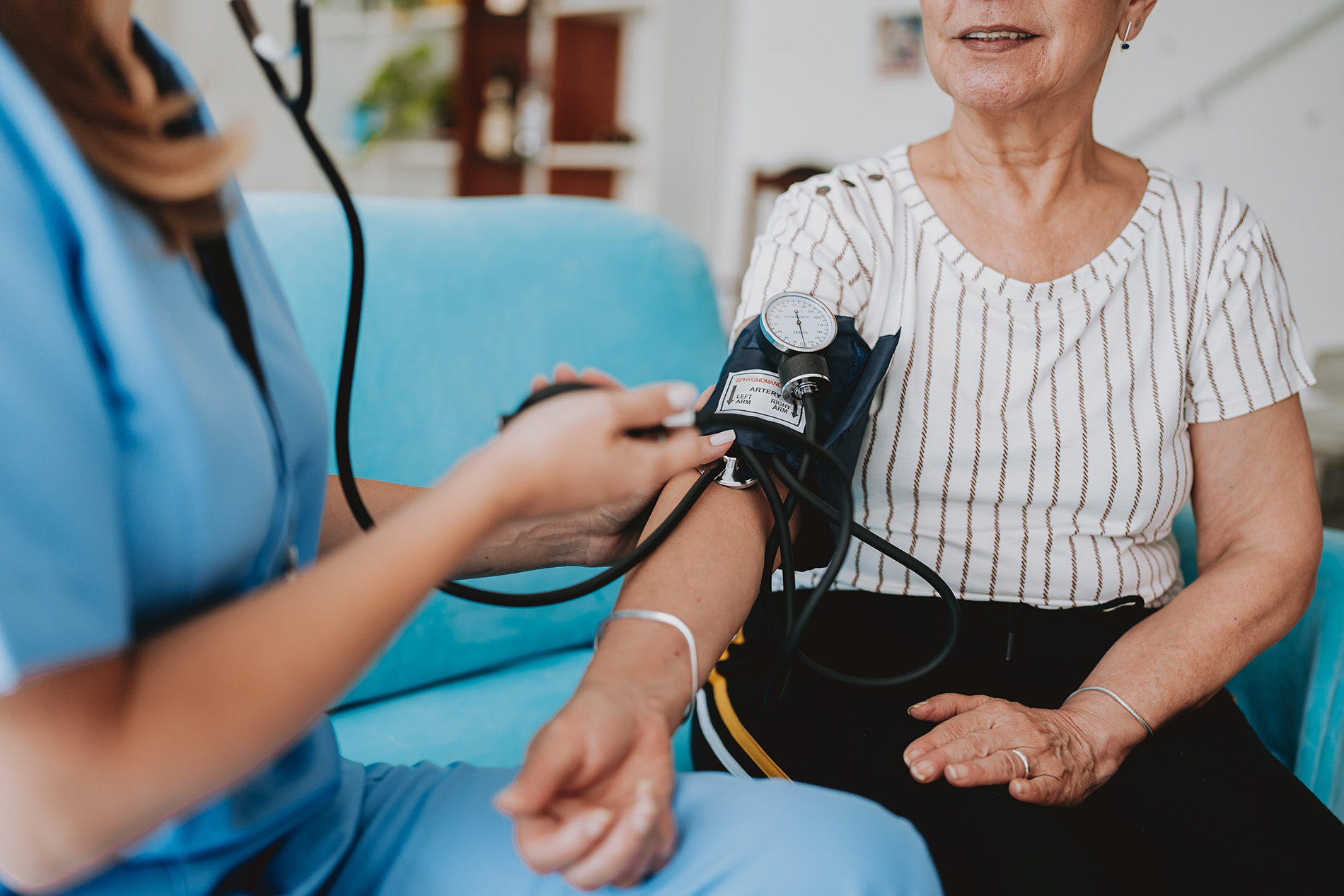 A healthcare worker checks an older woman's blood pressure using a cuff and stethoscope.