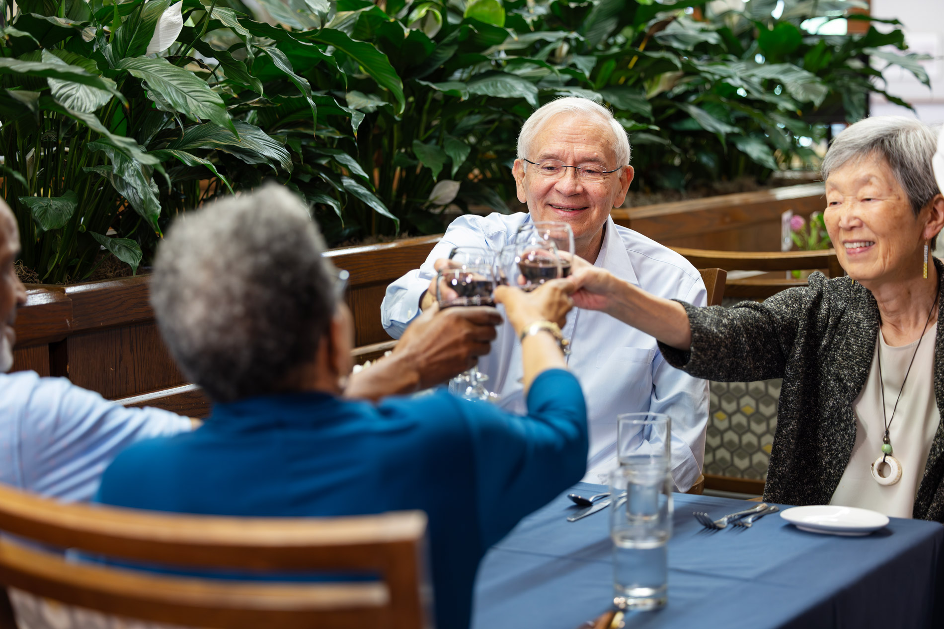 Four people sitting at a table clinking glasses together in a celebratory toast.