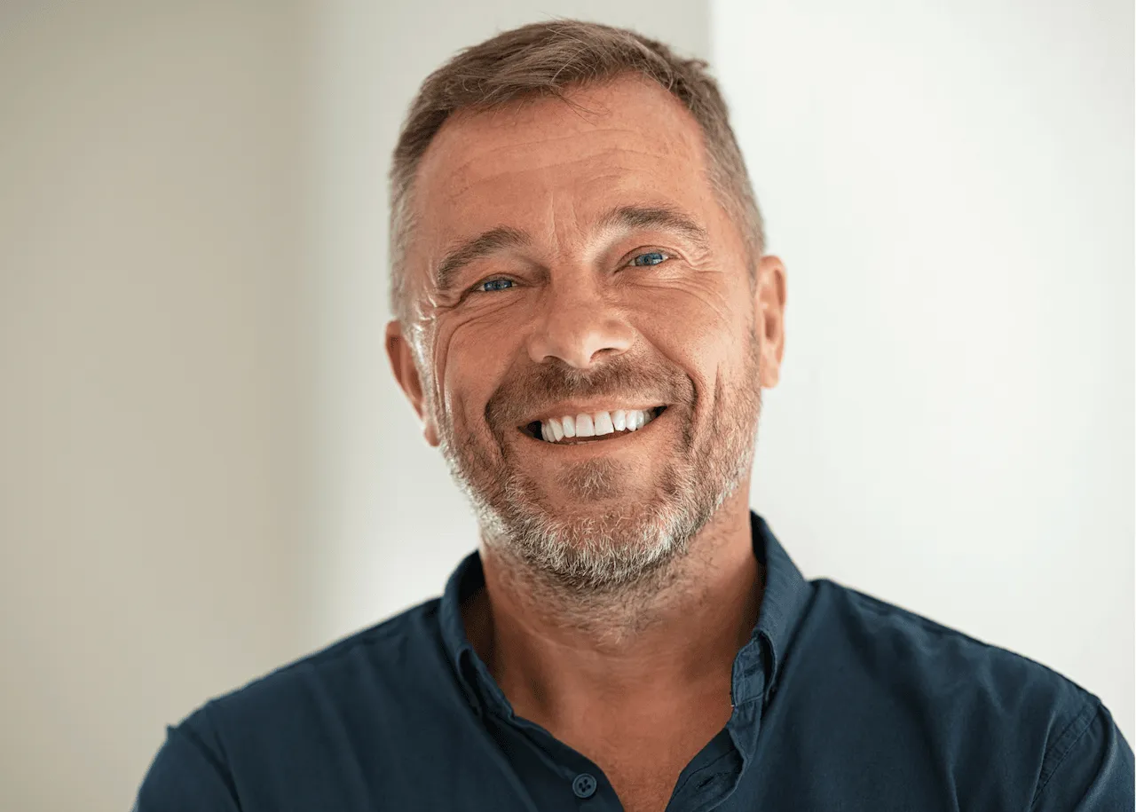 A middle-aged man smiling confidently, representing successful restorative dentistry treatments such as crowns or implants.