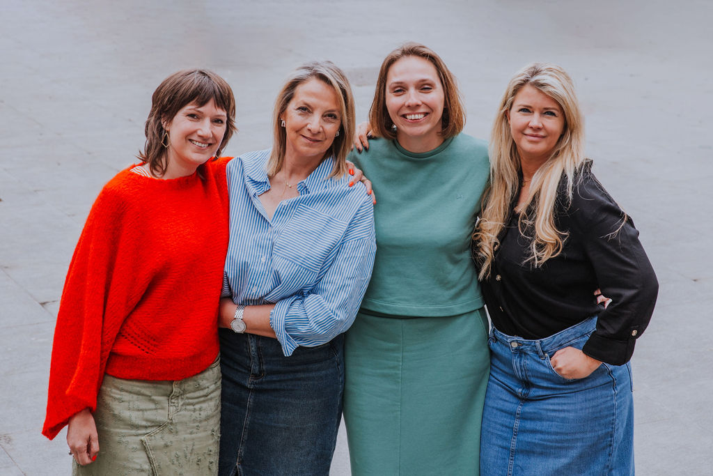 Team of four professional women smiling outdoors, representing a diverse and collaborative workplace. Business-casual attire highlights a modern company culture focused on teamwork, leadership, and women in business. Ideal for branding, corporate websites, or diversity and inclusion content.