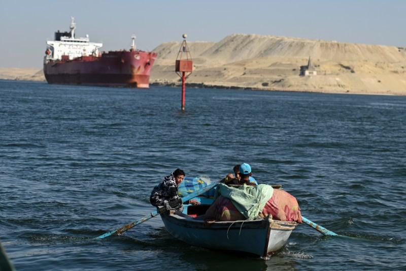 A small boat is seen as a ship transits the Suez Canal toward the Red Sea near Ismailia, Egypt.