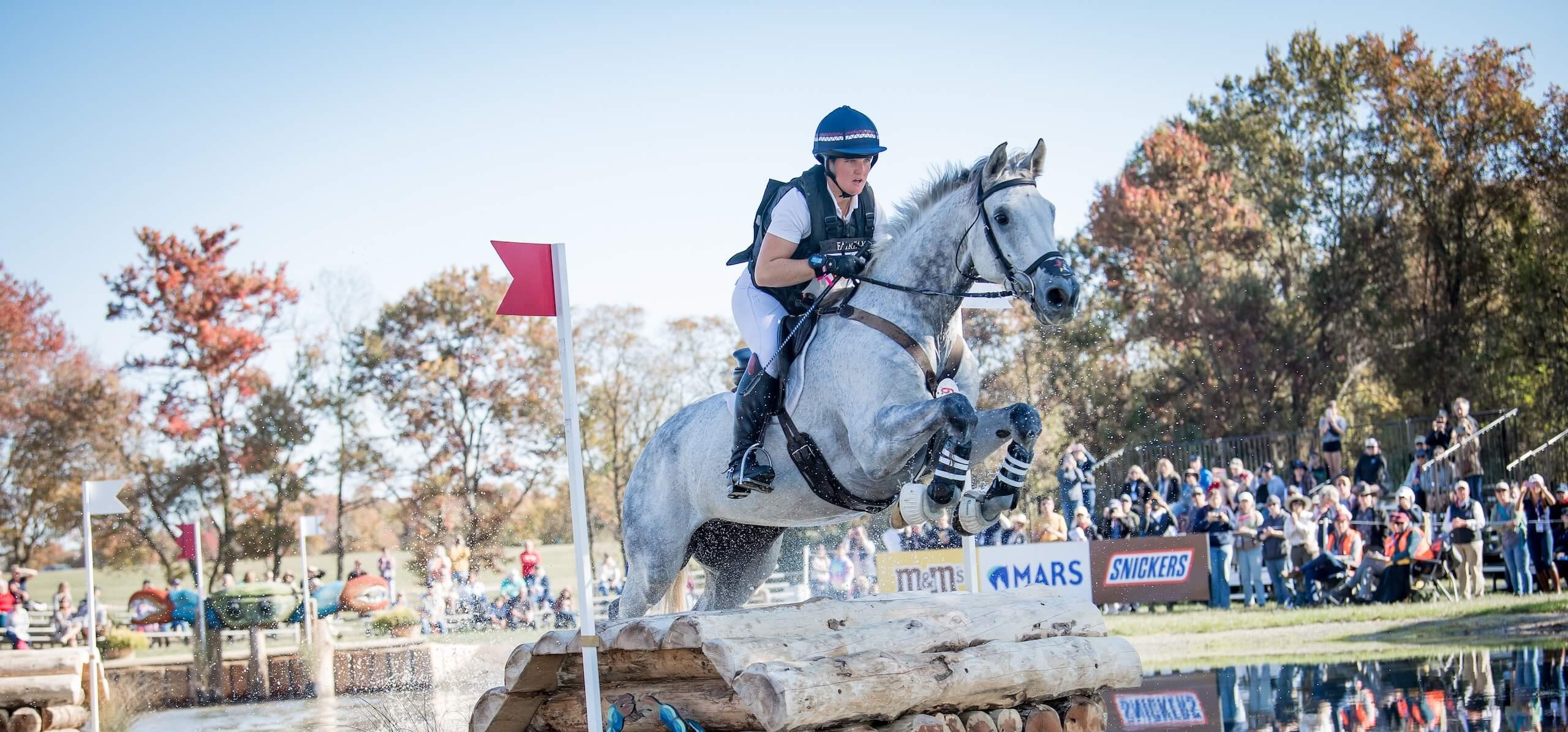 Women riding horse jumping over obstacle
