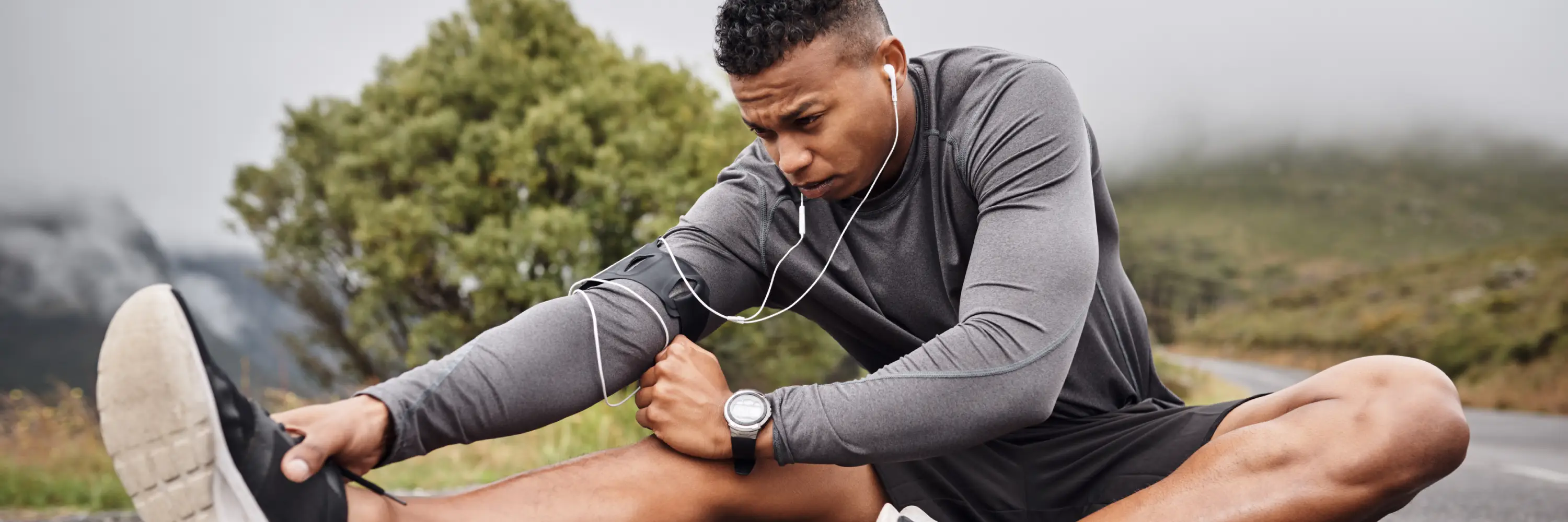 Runner stretching hamstring outdoors, highlighting the role of hip and leg mobility in supporting healthy running mechanics