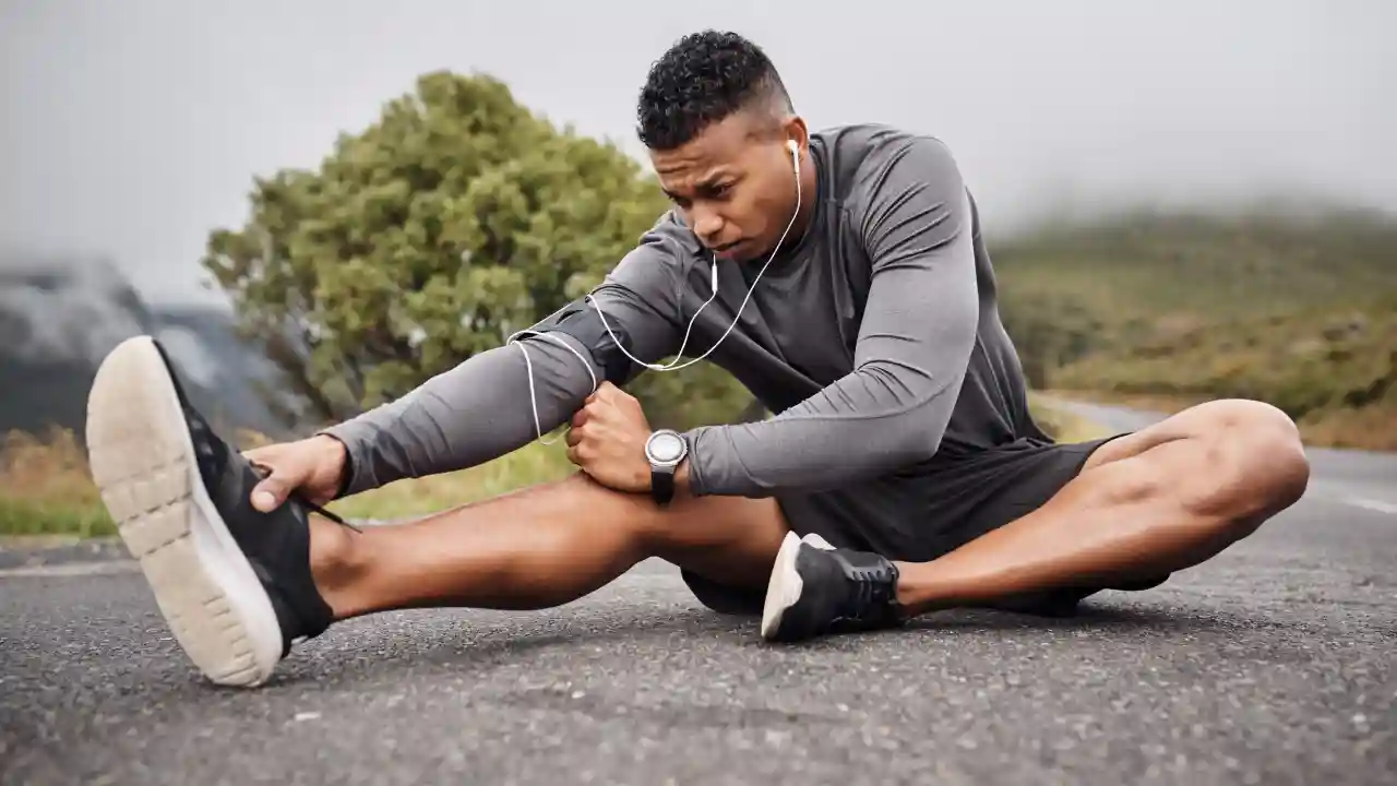 Seated runner holding a hamstring stretch, emphasizing post-run mobility to maintain hip flexibility and stride efficiency
