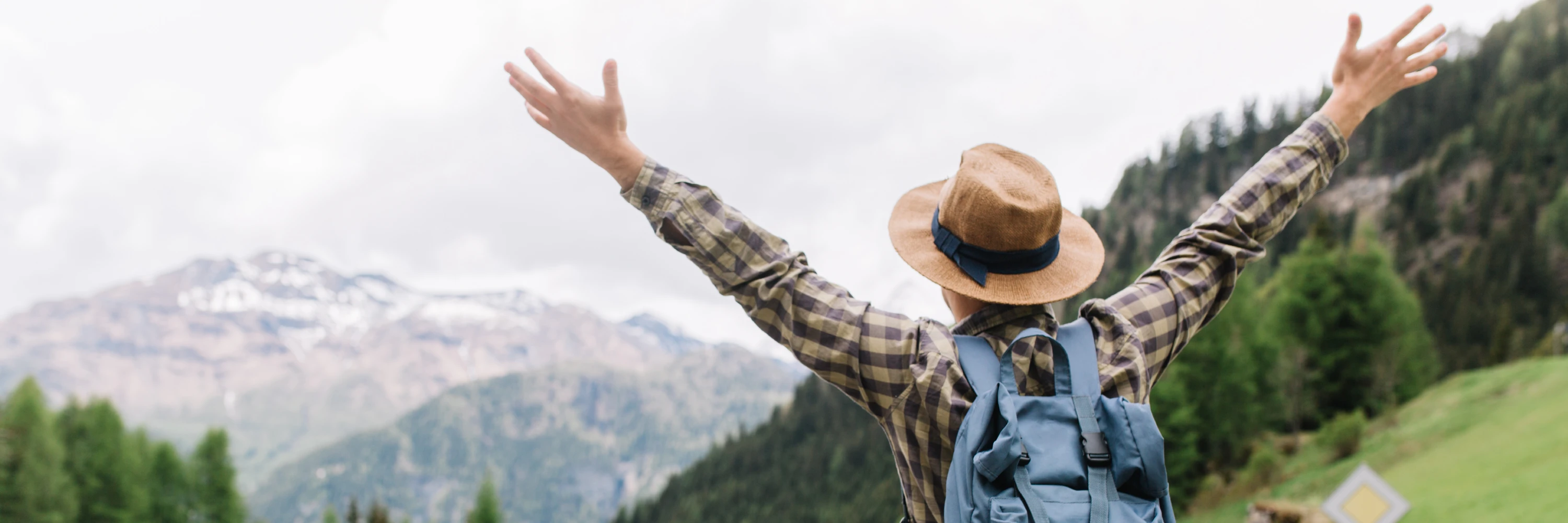 Traveler with arms raised on a mountain road after using a daily movement routine to stay energized while exploring.