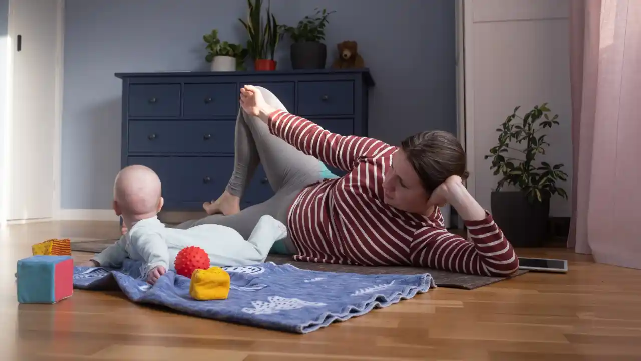 Mother on the floor with her baby, demonstrating how to add simple movement and stretching into playtime at home.