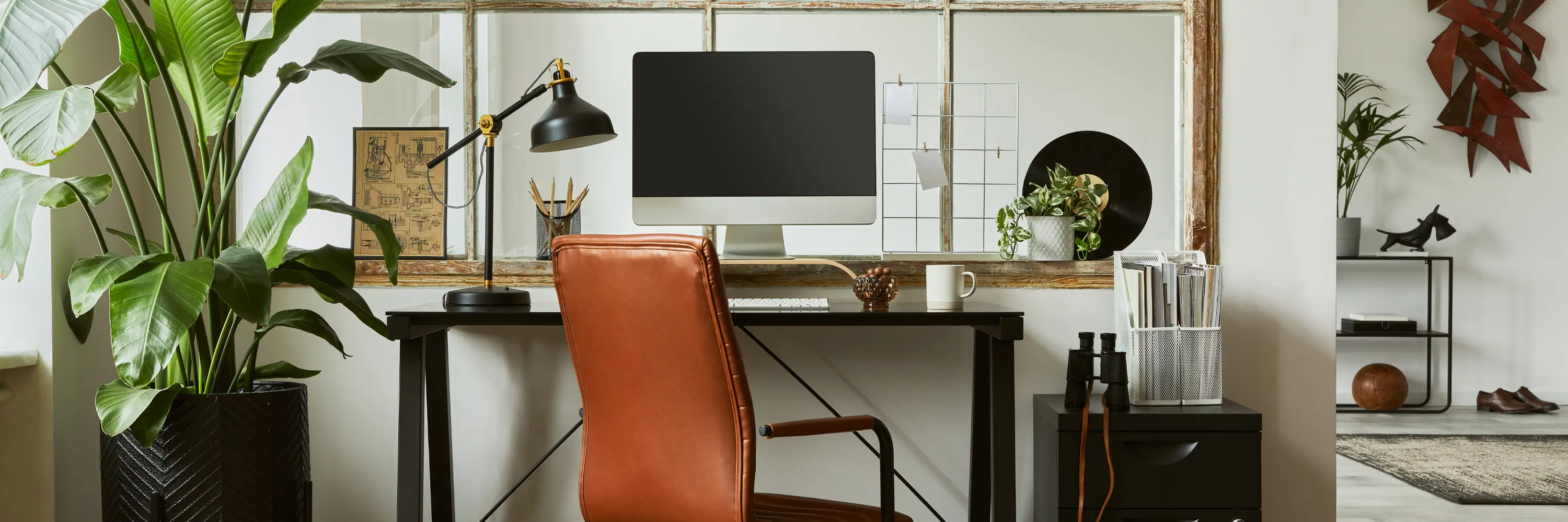 Modern home office with ergonomic chair, standing desk setup, and plants—example of a movement-friendly workspace.