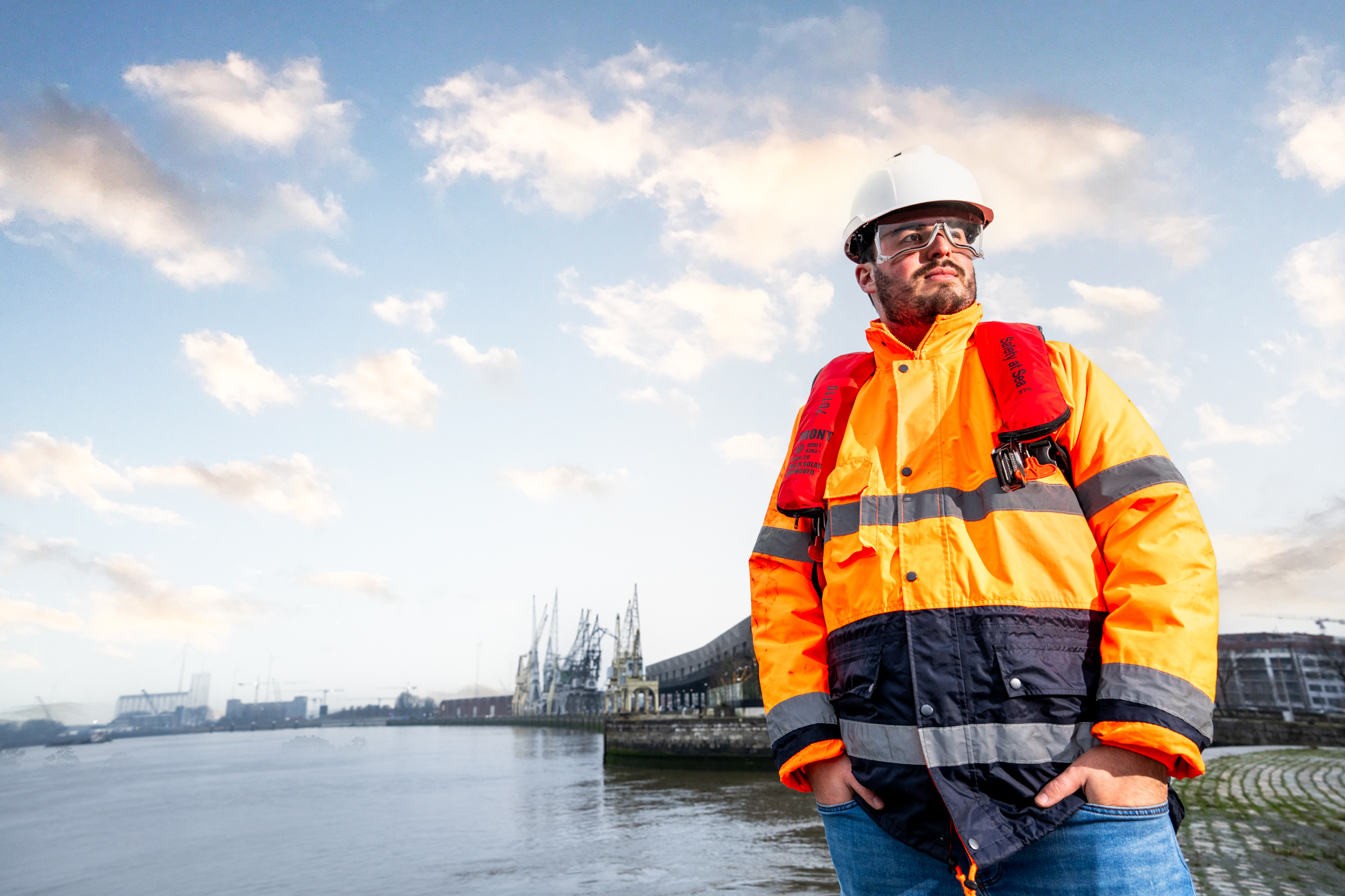 Havenarbeider met veiligheidsvest en helm aan het water