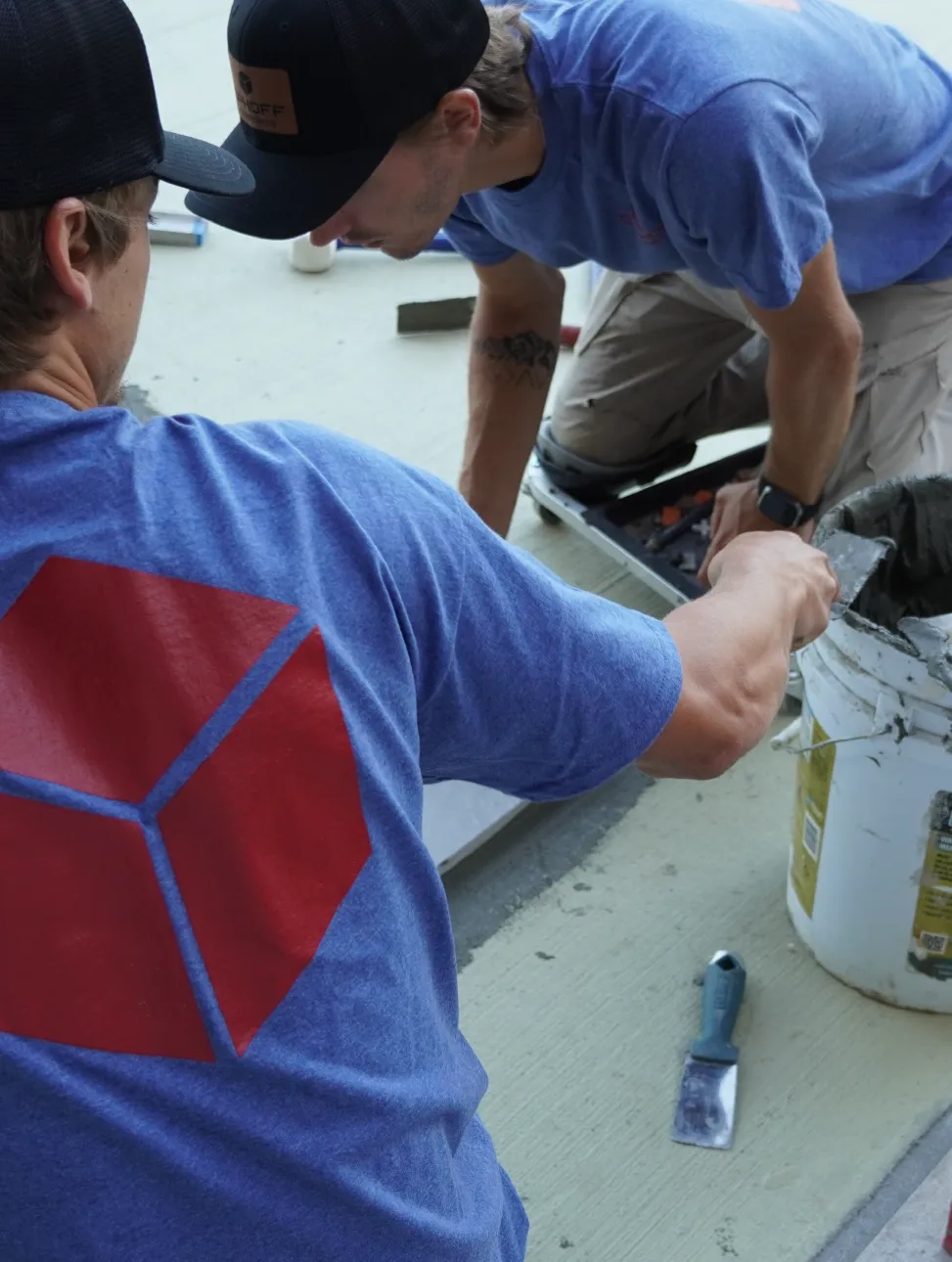 Two masons at Ophoff Companies working on a stone tile project