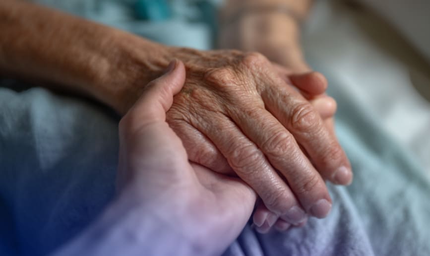 An older person holding the hand of a younger person.