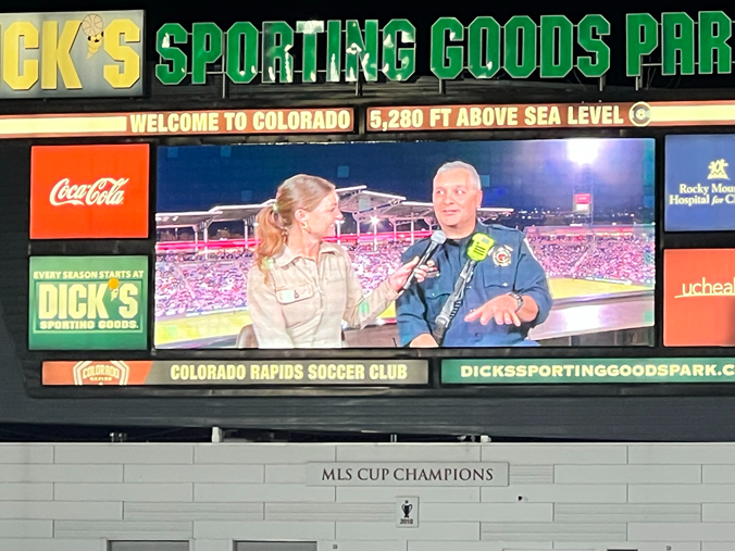A large screen displays a sports interview during a soccer match