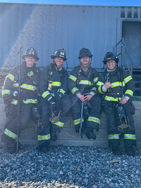 Four firefighters standing in front of a shed