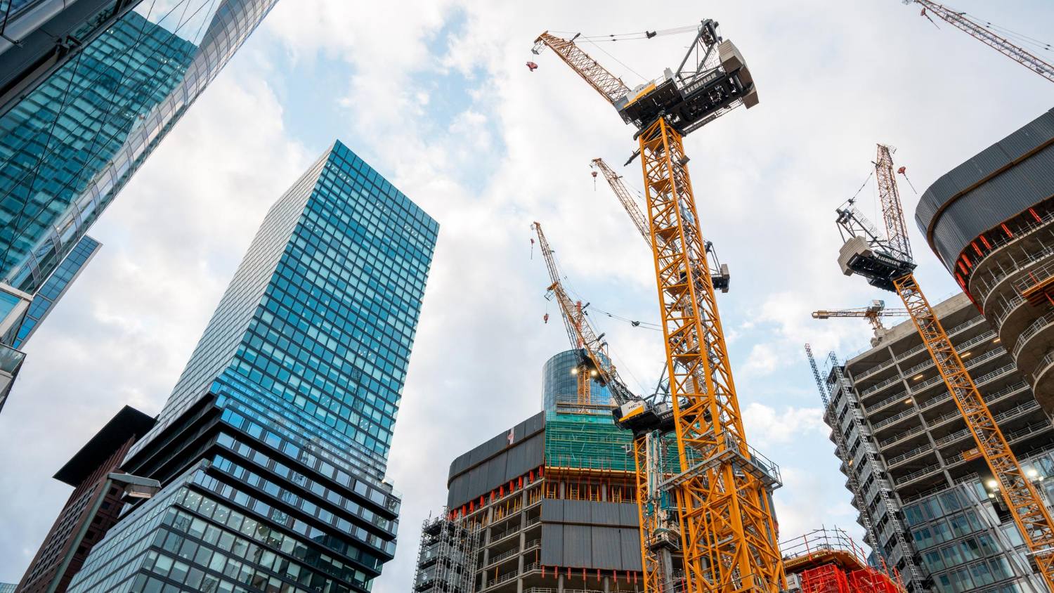 Multiple tower cranes and high-rise buildings under construction in a modern urban skyline