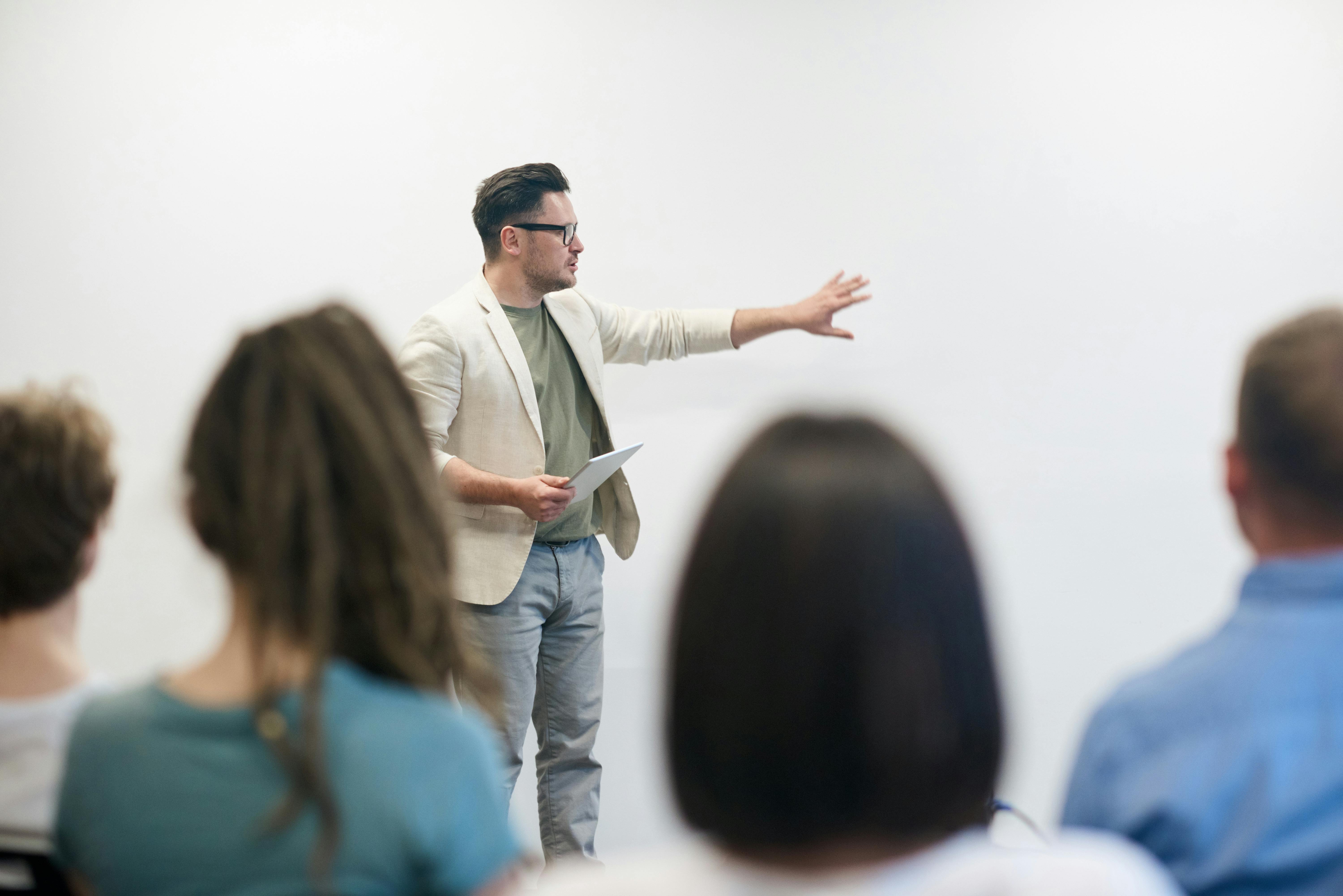 Man presenting in front of a whiteboard during a business workshop with an audience listening