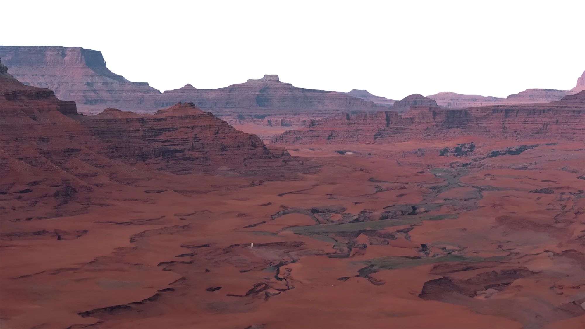 Expansive red rocky canyon landscape with layered cliffs under a clear blue sky.