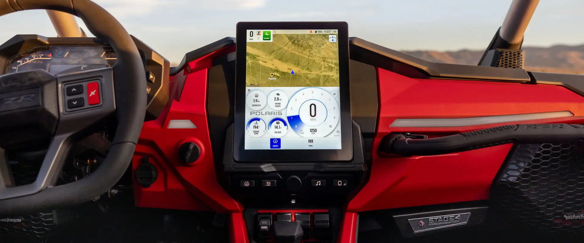 Dashboard of a red Polaris vehicle featuring a central touchscreen displaying navigation and vehicle stats including speed, engine hours, and temperature.