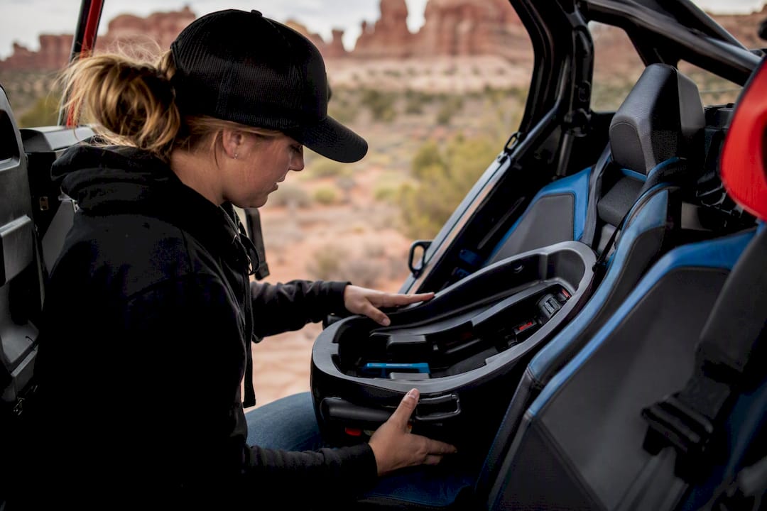 Hands checking car seat safety inside UTV