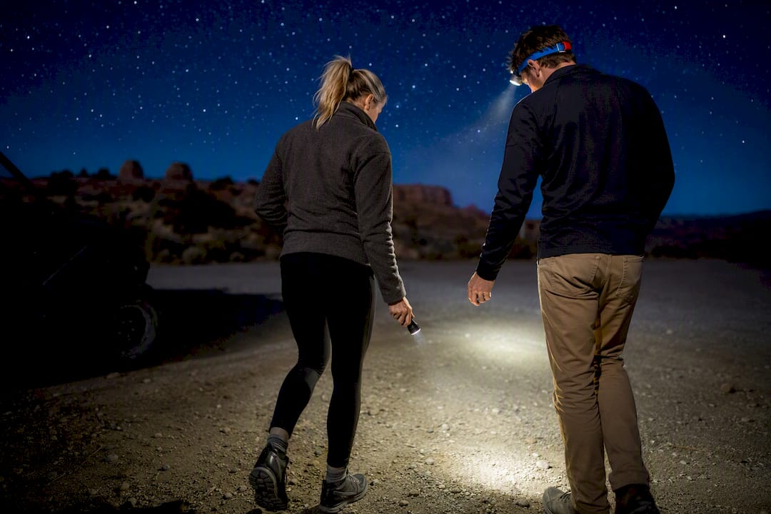 Couple using lights at dark trailhead