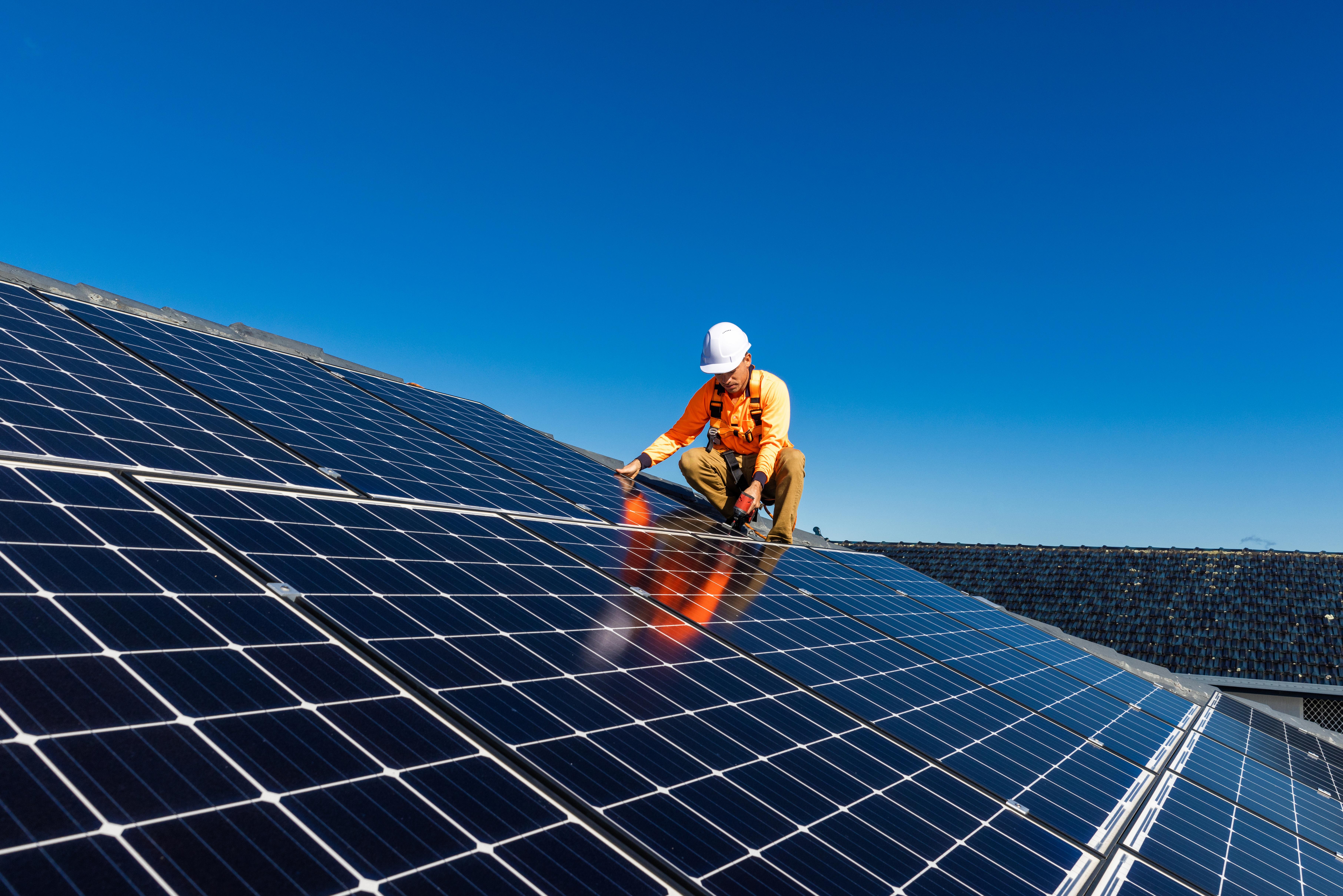 Technician working on solar panels during a rooftop removal and reinstallation.
