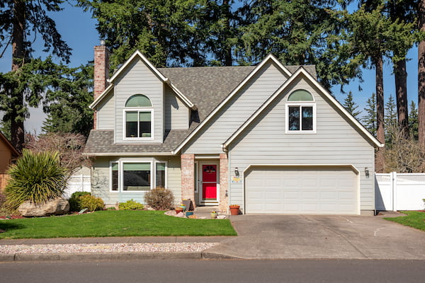 Light gray Oregon home with gable roof and red door, representing Rime Roofing & Exteriors’ service area.